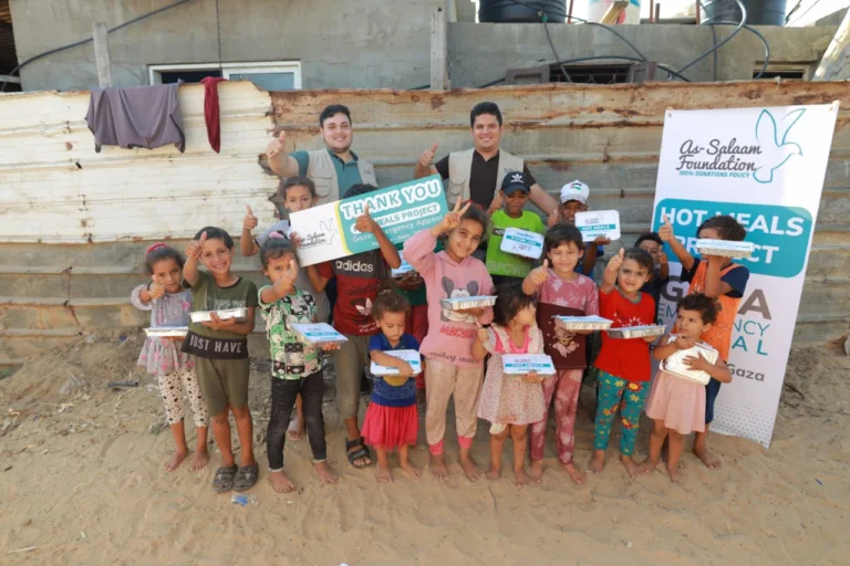 Lots of happy children stood with their hot meals and a thank you sign as part of As-Salaam's warmth project.