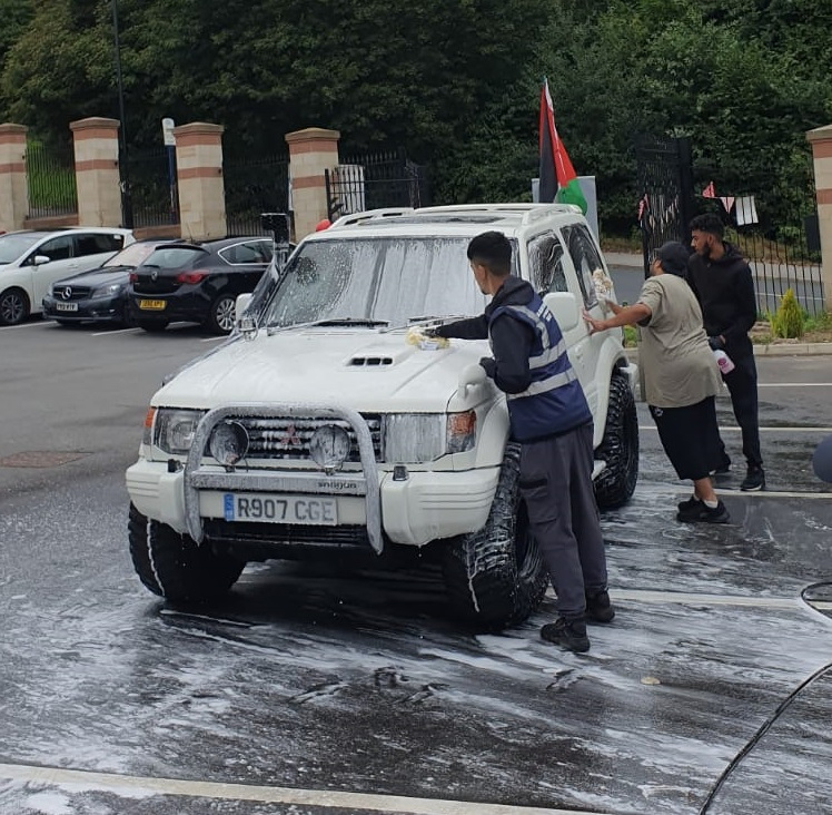 Volunteers from As-Salaam Humanitarian Foundation washing a car as part of a charity car wash